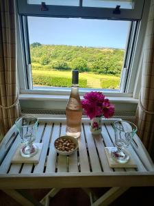 a bottle of wine on a table in front of a window at Elmsleigh in Marhamchurch