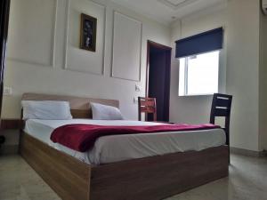 a bedroom with a bed with a red blanket on it at Hotel Sahajtam Inn in Sonīpat