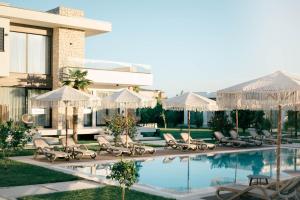 a pool with chairs and umbrellas next to a building at La Mandarine in Ulcinj