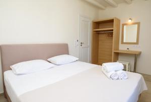 a bedroom with a white bed with towels on it at "Araklos" Summer houses in Aegiali