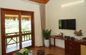 a living room with a large window and a television at Hoa Binh Resort in Hòa Bình