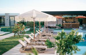 a row of lounge chairs with umbrellas next to a pool at La Mandarine in Ulcinj
