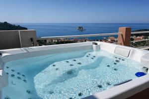 a hot tub on a balcony with the ocean in the background at Villa Blue Vista Meerblick mit Jacuzzi in Petrovac na Moru
