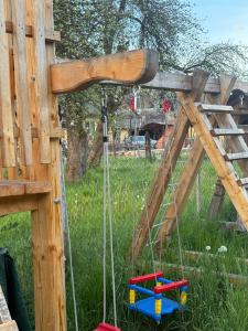 a swing set in a garden with a wooden structure at Domeniul Ursului in Vadu Izei