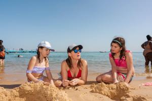 three girls playing in the sand on the beach at MinaMark Beach Resort for Families and Couples Only in Hurghada