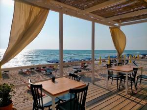 a wooden deck with tables and chairs on the beach at Brezza d'amare a lovely accommodation in Anzio in Anzio