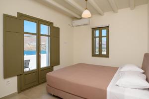 a bedroom with a bed and a window at "Araklos" Summer houses in Aegiali
