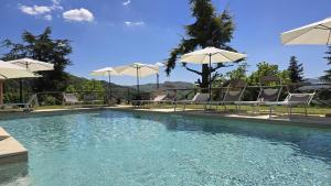a swimming pool with chairs and umbrellas at La Casetta Agriturismo in Santa Sofia