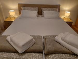 ein großes weißes Bett mit zwei Kissen und zwei Lampen in der Unterkunft Joy4You in Čilipi