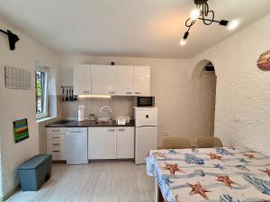 a kitchen with white cabinets and a table with a bed at Villa Gromaca in Omišalj