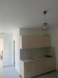 a kitchen with white cabinets and a sink and a light at Guesthouse Oasis in Baks-Rrjoll