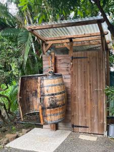 ein großes Holzfass neben einem Holzschuppen in der Unterkunft La Tiny Kay in Saint Esprit