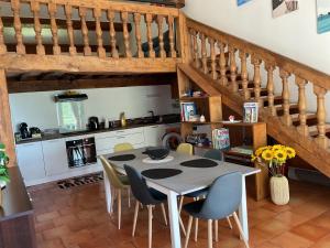 a kitchen with a table and chairs and stairs at Maison en pierre cosy chez Laëtitia in Auros