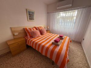 a bedroom with a bed with an orange and white striped blanket at La Turia Soleada in Cullera +25 photos