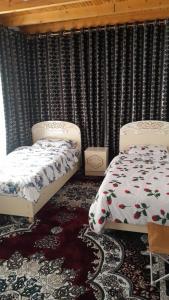 two beds in a room with curtains andskirtsomalyomaly at Gasthaus Jasur,Yakkakhona in Madovra