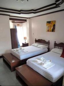 two beds in a hotel room with two tables at JM-RN Pensione House in Padre Burgos