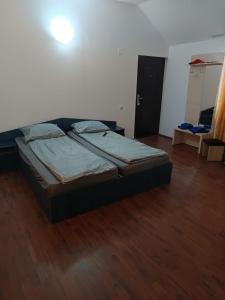 a bed in a room with a wooden floor at Căbănuțele Rotunda in Băile Herculane