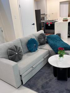 a living room with a gray couch with pillows on it at Palistic Paradise luxury private jacuzzi in Portmore