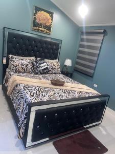 a large bed with a black headboard in a bedroom at Palistic Paradise luxury private jacuzzi in Portmore