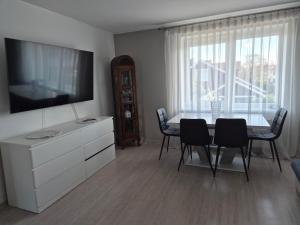 a dining room with a table with chairs and a television at Melnragė in Melnragė +8 photos