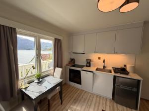 a kitchen with white cabinets and a table and a window at Hofslund Apartments in Sogndal
