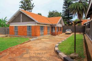 a house with an orange roof in a yard at Tenzi BnB in Jinja