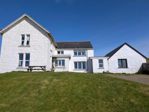 a white house with a bench in front of it at Scoor House - Cnoc Mor in Bunessan