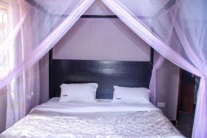 a bedroom with a canopy bed with white sheets and pillows at Tenzi BnB in Jinja