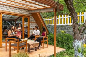 a group of people sitting on a wooden deck at The Social Stays Kasol in Kasol