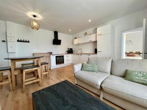 a living room with a couch and a table and a kitchen at Le 200 de la cale in Fouesnant