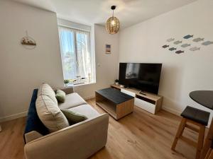 a living room with a couch and a flat screen tv at Le 200 de la cale in Fouesnant