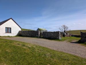 a house and a stone wall next to a field at Scoor House - Laggan in Bunessan