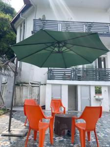 a green umbrella and three orange chairs under a table at BlueWave Villa in Kangra