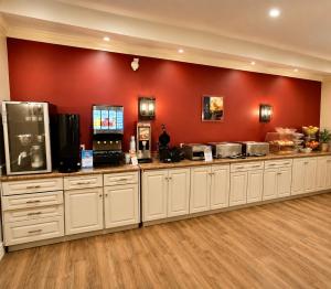 a kitchen with white cabinets and a red wall at Best Western Kincardine in Kincardine