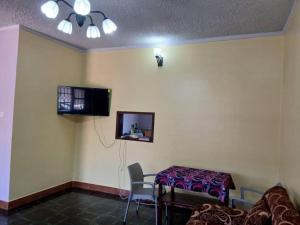 a room with a table and a tv on the wall at Tenzi BnB in Jinja