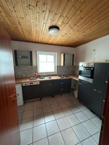 a kitchen with black cabinets and a wooden ceiling at ME Apartments - Big Space in Bad Camberg