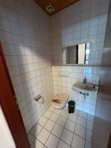 a white tiled bathroom with a sink and a toilet at ME Apartments - Big Space in Bad Camberg