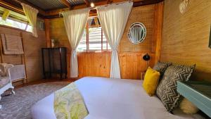 a bedroom with a white bed and a window at Crabb Cottage and escape in St Lucia