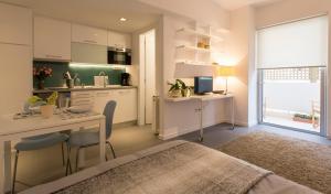 a bedroom with a bed and a desk and a kitchen at Homz Studios Faliro in Athens
