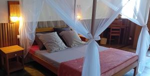 a bedroom with a bed with a canopy at Ecolodge Nosy Faly in Nosy Be