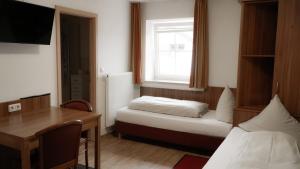 a small room with a bed and a desk and a window at Zum Hopfenbauer in Rudelzhausen +4 photos