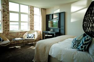 a bedroom with a bed and a television and a chair at Van der Valk Hotel Apeldoorn in Apeldoorn