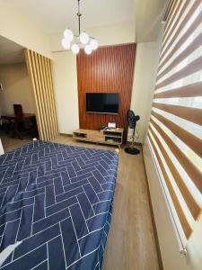 a bedroom with a blue bed and a flat screen tv at Refreshing Condo hotel in General Trias