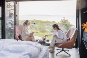 two women sitting in chairs in a room with a table at Torvika Seaview Pods in Bølandet