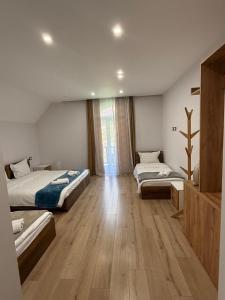 a bedroom with three beds and a wooden floor at Stonehouse villa in Valbonë