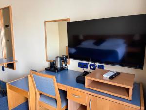 a hotel room with a desk and a large tv at Tamaris Rooms in Zadar