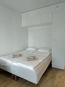 a white bed in a room with white walls at Foliate Living Varpu in Jyväskylä