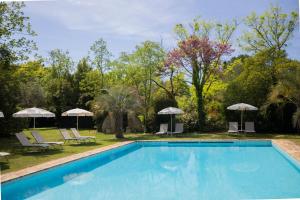 a swimming pool with chairs and umbrellas at Hôtel - Restaurant & Spa La Magdeleine - Mathias Dandine in Gémenos