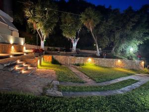 a garden at night with a stone pathway and palm trees at Spiros Rooms in Kastrosikia