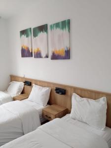 three beds in a room with paintings on the wall at Beach breeze in Essaouira